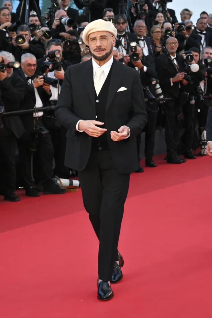 John Travolta Cannes 2026 Beret Look — The Viral Fashion Moment With the Most Heartwarming Story Behind It John Travolta ivory beret suit